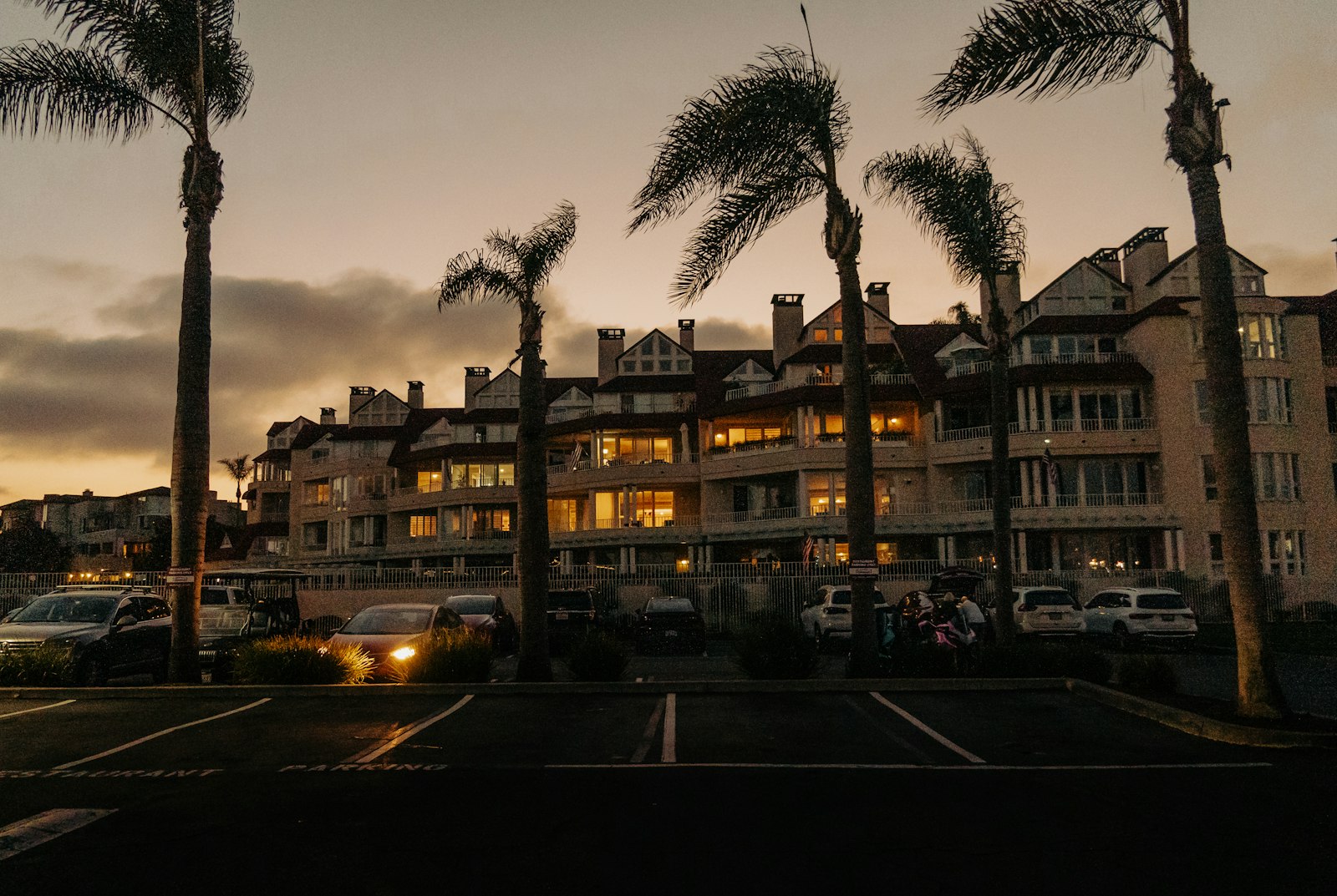 A residential community with palm trees at sunset, its parking lot in the foreground